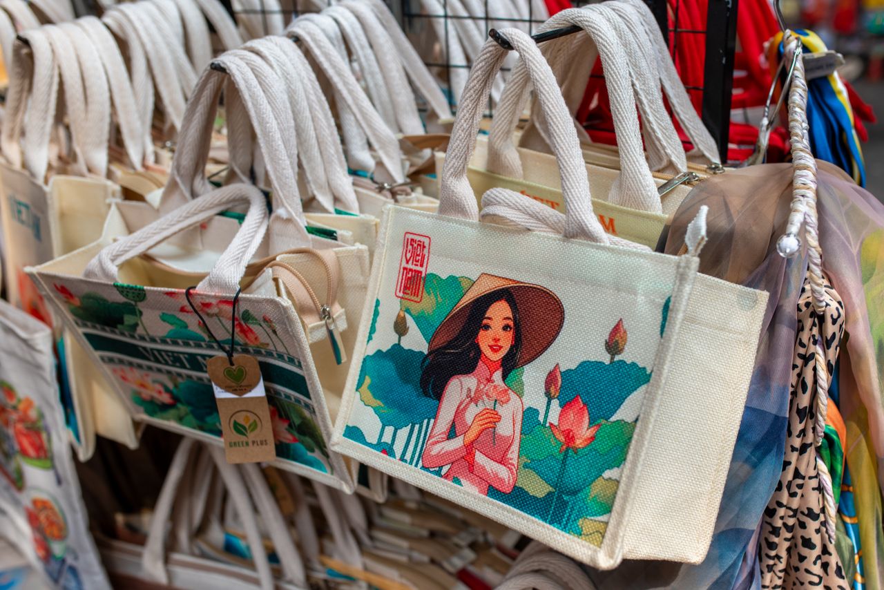 Vibrant canvas tote bags with artistic designs on display in a market.